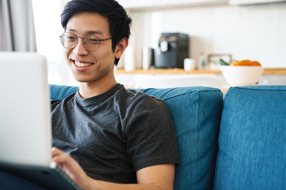 happy-employee-on-computer-couch-min